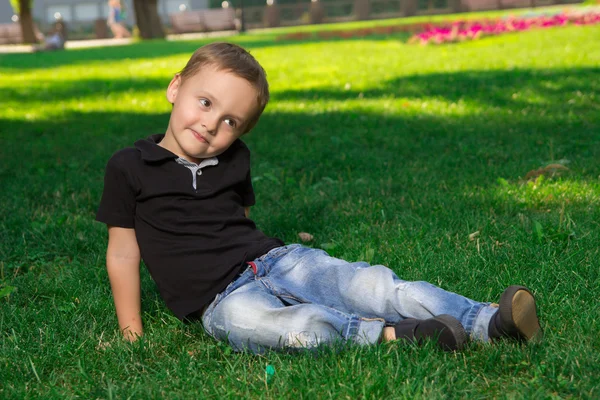 Nachdenklicher kleiner Junge sitzt auf dem Gras — Stockfoto