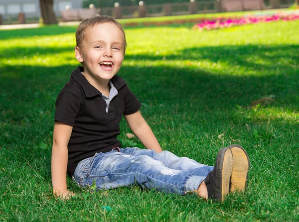 草の上に座っている笑顔の小さな男の子 — ストック写真