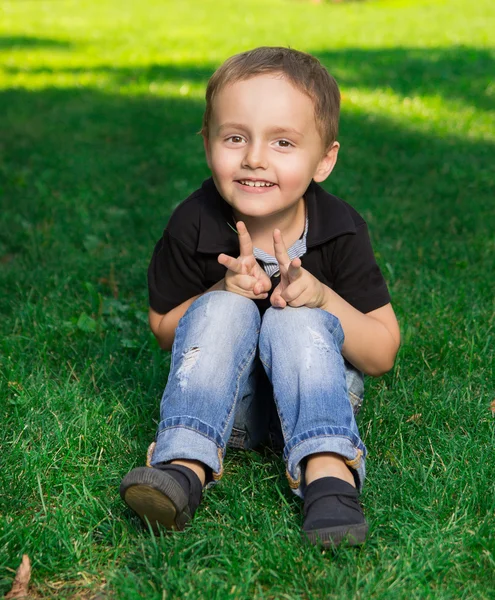 Niño sonriente sentado en la hierba —  Fotos de Stock