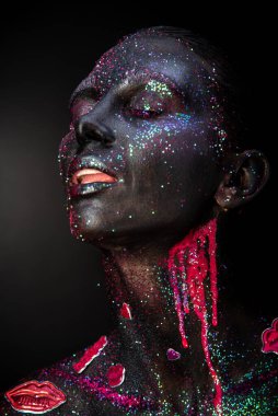 Mystical woman makeup with sparkles and luminous elements on a dark background