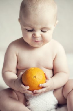 yatakta oturmuş ve bir portakal izlerken şirin bebek