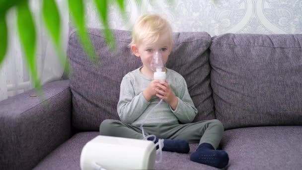 Roztomilý malý blonďatý chlapec dělá inhalaci doma. — Stock video