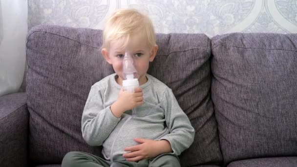 Roztomilý malý blonďatý chlapec sprejování onemocnění dýchacích cest doma. — Stock video