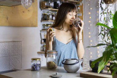 Mavi elbiseli genç bayan bitki çayı yapar..