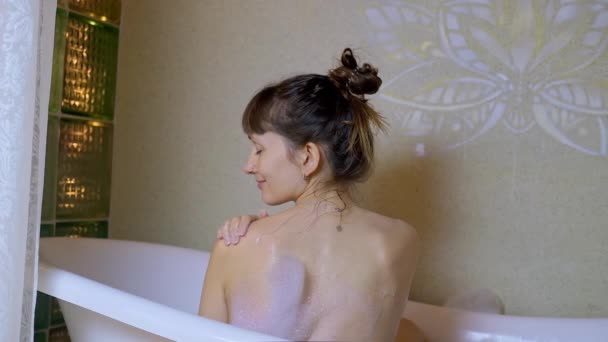 Back view of brunette woman relaxing in bathtub with foam. — Stock Video