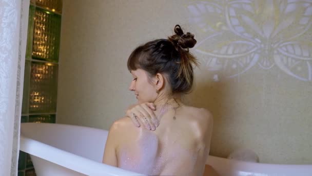 Zadní pohled brunetky ženy relaxující ve vaně s pěnou. — Stock video