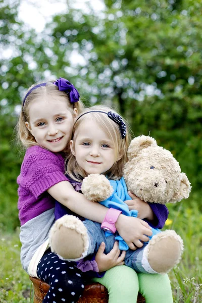 Маленькие улыбающиеся девочки с медвежьей игрушкой — стоковое фото