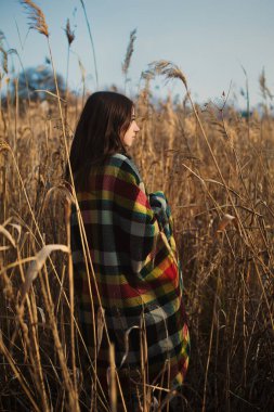 Pampa otlağında kareli sıcak ekoseyle kaplı bir kız.