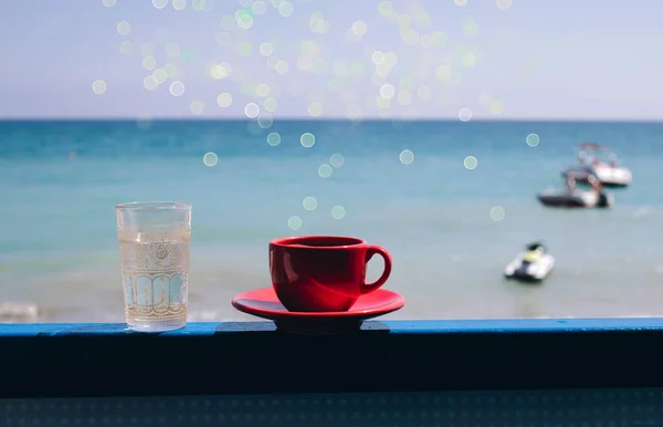 コーヒー 海の景色を望む水のガラスの赤いカップ 休暇中の魔法の朝の朝食 — ストック写真