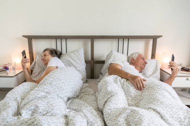 Yaşlı evli çift, erkek ve kadın, evde yatakta birlikte uyur. Cinsel problemler, sinir bozukluğu, akıllı telefon.