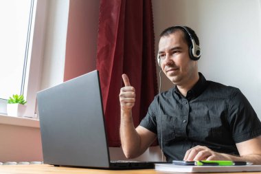 Ana konu bulanık, genç erkek masa başında oturuyor, ev bilgisayarı online dizüstü bilgisayar iş mesafesi video görüşmesi.