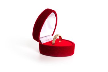 Kırmızı kalp şeklinde bir mücevher kutusunda beyaz bir arka planda izole edilmiş altın bir alyans..