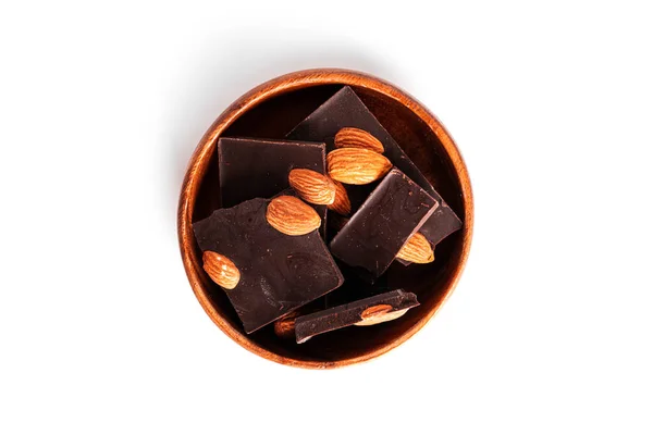 Kakaolu siyah çikolata ve beyaz arka planda izole edilmiş badem. Tahta kasede çikolata parçaları. — Stok fotoğraf