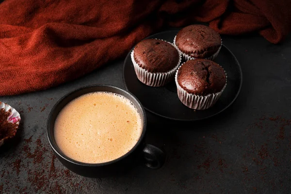 Koyu arkaplanda çikolatalı kekler olan kahve. Frenk üzümlü çikolatalı kek..