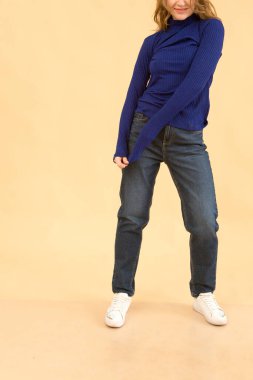 Stüdyonun arka planında kıyafet provası yapan bir kadın var..