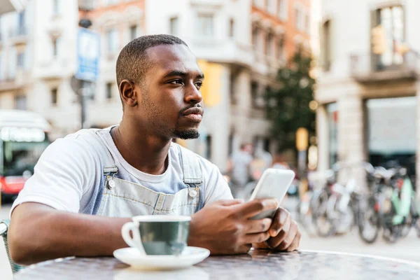 Молодий афро-чоловік використовує телефон на терасі бару — стокове фото