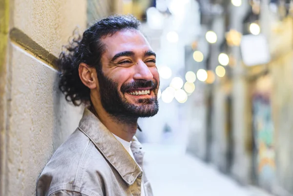 Cheerful Hispanic male leaning on wall
