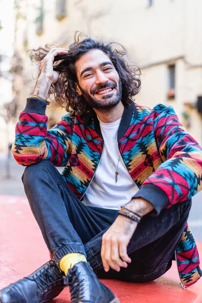 Trendy Hispanic man touching hair on street
