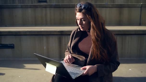 Орієнтована жінка використовує ноутбук на кроках — стокове відео
