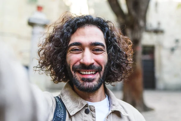 Neşeli adam sokakta selfie çekiyor.