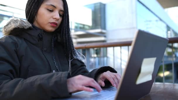 Allvarlig etnisk kvinna skriva på bärbar dator medan du arbetar på distans — Stockvideo