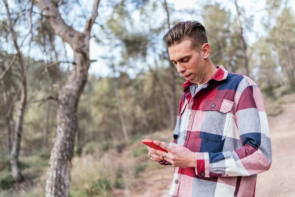 Hombre serio navegando teléfono inteligente en el bosque — Foto de Stock