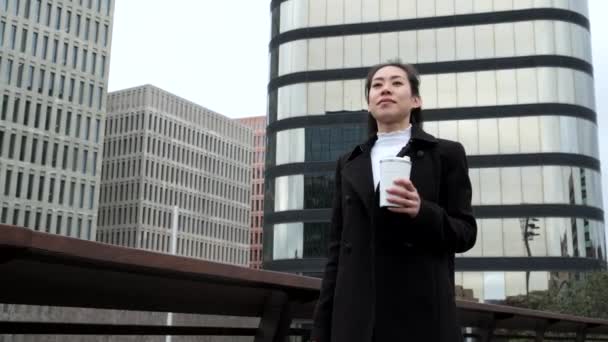 Chinese businesswoman with hot drink walking on bridge — Stock Video