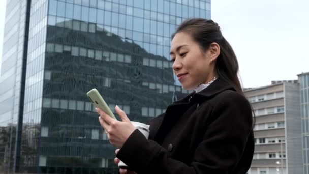 Азійська комерсантка користується смартфоном у центрі міста. — стокове відео