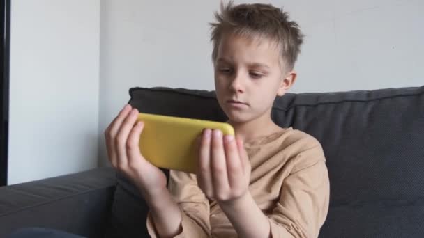 Băiat folosind telefonul mobil pe canapea — Videoclip de stoc