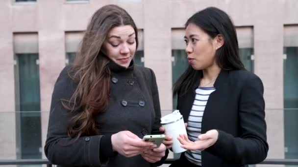 Diverse women browsing smartphone together in street — Stock Video