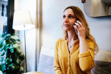 Kafeteryada telefonla konuşan genç ve güzel bir kadın.