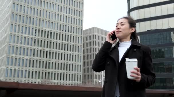 Positive Chinese businesswoman answering phone call on street – Stock-video