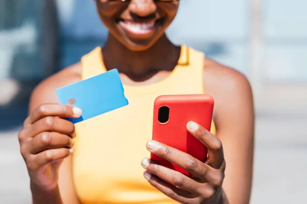 smart phone and credit card on the hands of an unrecognizable african woman. Concept of online shopping