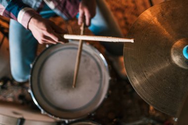 Yüksek ekin açılı, tahta bagetleriyle sahnede rock müzik çalan isimsiz bir erkek müzisyen.