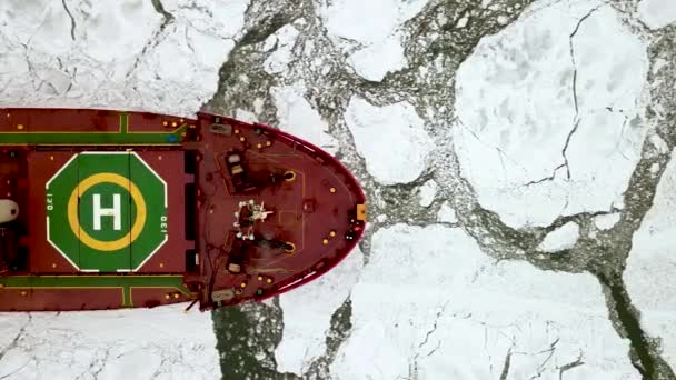 Drone top down épico rompehielos de acero rojo buque cisterna rompe el invierno mar congelado, supera. El arco de la nave flota a través del témpano de hielo. Enorme bloque blanco de hielo. — Vídeo de stock