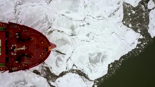 Drone top down épico rompehielos de acero rojo buque cisterna rompe el invierno mar congelado, supera. El arco de la nave flota a través del témpano de hielo. Enorme bloque blanco de hielo. — Vídeo de stock