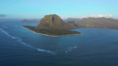 Hava görüntüsü. Gün batımında cennet gibi kayalık tropikal ada. Gün batımında okyanus dalgaları ve Le Morne Brabant. Mauritius.
