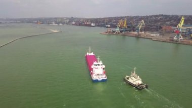 Kargo gemisinin kargo limanından özel okyanus konsepti nakliye gemilerine ihracat malları için römorkör ile çalışan havadan görüntüsü.