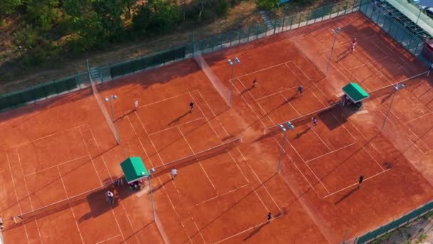 Joueurs de tennis en action pendant le match sur le stade professionnel. Vue aérienne. Les joueurs jouent au tennis sur un terrain orange. — Video