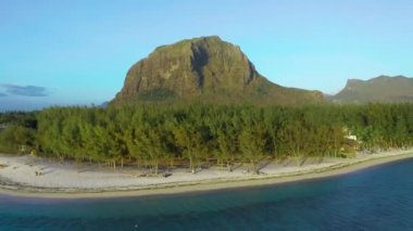 Hava görüntüsü. Gün batımında cennet gibi kayalık tropikal ada. Gün batımında okyanus dalgaları ve Le Morne Brabant. Mauritius.