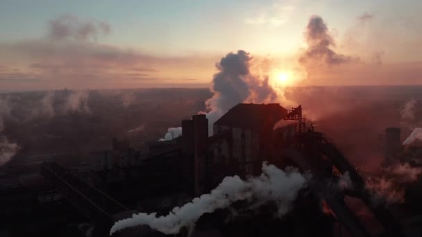 Беспилотник вокруг токсичных труб предприятия, трубящихся на фоне неба, выпускает дым. Завод загрязняет окружающую среду. Вид с воздуха — стоковое видео