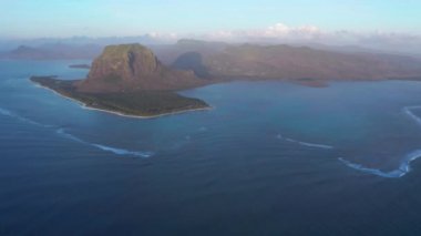 Hava görüntüsü. Gün batımında cennet gibi kayalık tropikal ada. Gün batımında okyanus dalgaları ve Le Morne Brabant. Mauritius.