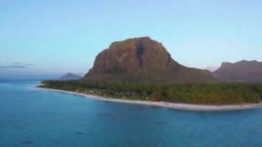 Hava görüntüsü. Gün batımında cennet gibi kayalık tropikal ada. Gün batımında okyanus dalgaları ve Le Morne Brabant. Mauritius.