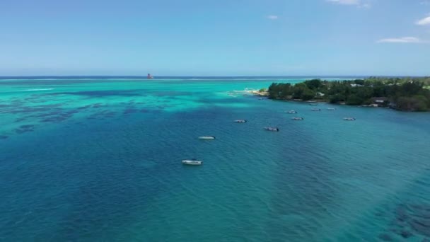 Vista aérea do oceano na Maurícia. Água azul-turquesa com bancos de areia, recifes e uma ilha. Voando em torno de um barco wakeboarding — Vídeo de Stock