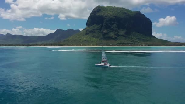 Catamarano in acque turchesi sullo sfondo dell'isola paradisiaca Mauritius. Drone filmato aerea vista dall'alto del catamarano vela in mare aperto. — Video Stock