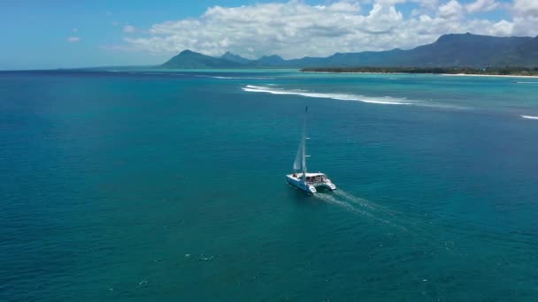 熱帯の海でカタマランを帆を開いてセーリングし、ドローンからの眺め。モーリシャス — ストック動画