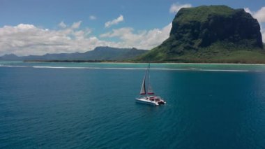 Mauritius adasının arka planında turkuaz su katamaranı var. İHA görüntüleri açık denizde yüzen katamaranların havadan görüntüsü..