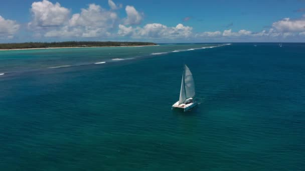 Katamaran i turkost vatten mot bakgrund av paradisön Mauritius. Drone film antenn ovanifrån av katamaran segling i det öppna havet. — Stockvideo