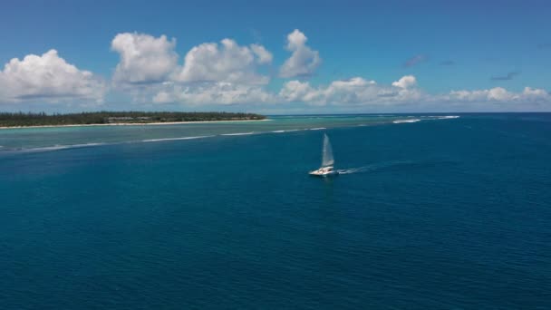 Catamarano in acque turchesi sullo sfondo dell'isola paradisiaca Mauritius. Drone filmato aerea vista dall'alto del catamarano vela in mare aperto. — Video Stock