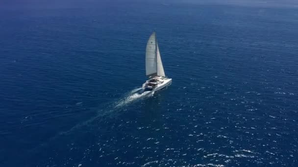 Caméra suivre catamaran dans l'eau bleue de l'océan. Le secteur des voyages se remet de la pandémie de coronavirus. Vidéo de drone vue aérienne du haut vers le bas. — Video